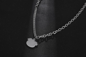 Detail of silver pumpkin pendant with mixed flat curb and rolo chain on black texture