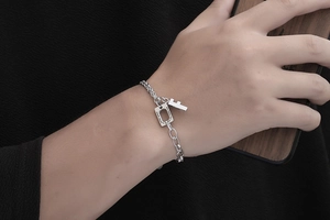Detail of silver titanium chain bracelet with F letter and engraved quote pendant