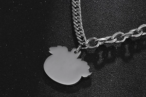 Macro detail of silver apple pendant with punk style chunky cuban link chain