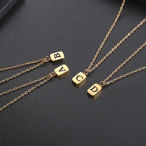 Vier minimalistische goldene rechteckige Buchstabenanhänger auf schwarzem Grund