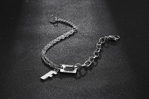 Macro detail of silver titanium steel chain bracelet with F charm and engraved tag
