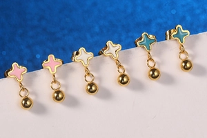 Macro shot of gold star stud earring with colorful enamel inlay and hanging bead detail
