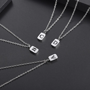 Silver stainless steel necklaces featuring engraved letter pendants A, B, C, D on a dark stone