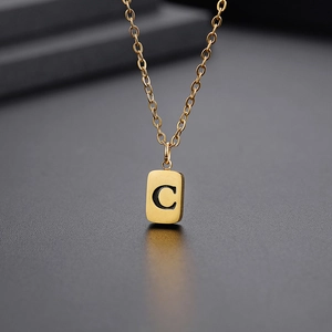 Makroaufnahme des goldene quadratische Anhängers mit Buchstabe C und feiner Kette