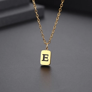 Makroaufnahme des goldenen quadratischen Anhängers mit graviertem E an einer feinen O-Kette