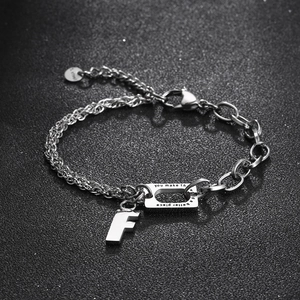 Asymmetric stainless steel letter bracelet with engraved plate on dark grey background