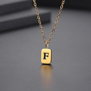 Detailaufnahme des goldenen quadratischen Anhängers mit eingraviertem F an einer O-Kette