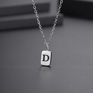 Close-up of a silver square pendant necklace with an engraved capital letter D
