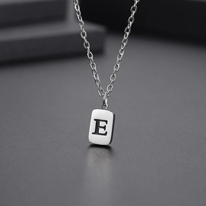 Macro view of silver rectangular pendant with engraved letter E on a link chain