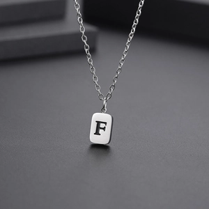 Close-up of a silver titanium steel necklace with an engraved letter F square pendant