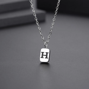 Macro view of silver stainless steel rectangular pendant with black engraved letter H