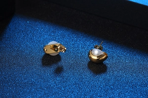 Vue détaillée de boucles d'oreilles élégantes en or avec perles blanches sur fond bleu