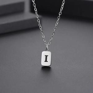 Macro detail of polished stainless steel rectangular pendant featuring engraved letter I