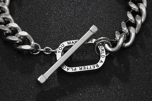 Macro view of silver stainless steel Cuban chain with engraved T-bar inspirational quote