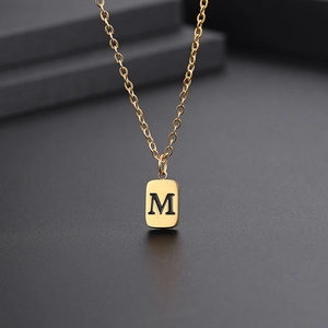 Makroaufnahme einer goldenen Halskette mit rechteckigem Buchstaben M Anhänger