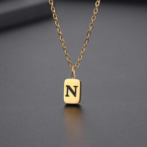 Detailaufnahme einer goldener quadratischer Halskette mit eingraviertem Buchstaben N auf Metall