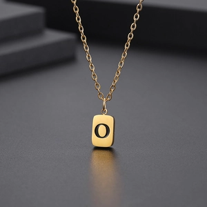 Detail einer goldenen quadratischen Anhängerkette mit fettem schwarzem Buchstaben O