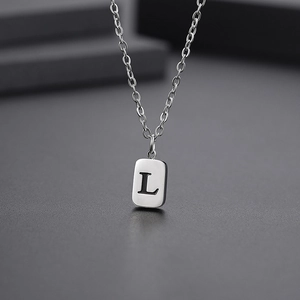 Detailed close-up of a silver stainless steel necklace with a rectangular letter L pendant
