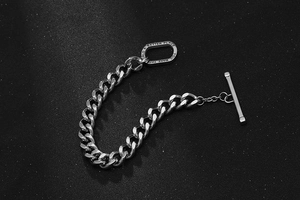 Macro detail of silver curb chain bracelet featuring engraved T-bar toggle clasp