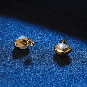 Élégantes boucles d'oreilles dorées en forme de coquille avec perle sur fond bleu foncé