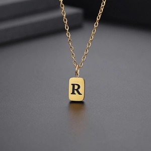 Makroaufnahme einer goldenen Halskette mit quadratischem Anhänger und Gravur Buchstabe R