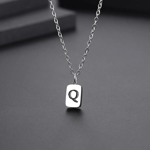 Macro shot of silver titanium steel letter Q pendant with polished finish and link chain