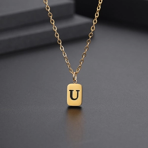 Makroaufnahme des minimalistischen goldenen Rechteckanhängers mit schwarzem Buchstaben U
