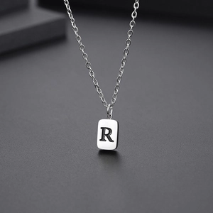 Macro shot of silver stainless steel pendant featuring a modern engraved letter R