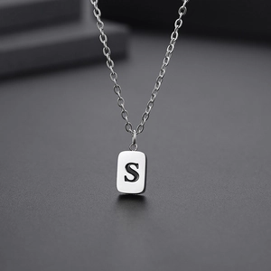 Macro shot of silver O-chain necklace featuring a minimalist rectangular S-letter pendant