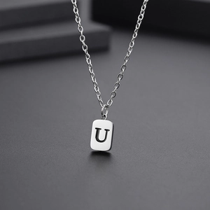 Macro shot of silver titanium steel rectangular pendant necklace with engraved letter U