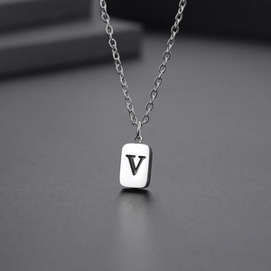 Close-up of a silver stainless steel rectangle pendant with engraved letter V