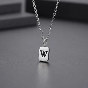 Detailed macro view of silver square pendant featuring engraved letter W with black filling
