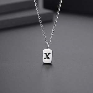Detailed macro view of silver titanium steel necklace featuring a black engraved letter X
