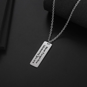 Collar con colgante rectangular de acero de titanio pulido y grabado sobre fondo gris oscuro