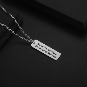 Collar minimalista de acero de titanio plateado con grabado inspirador sobre fondo negro