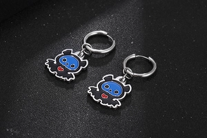 Dettaglio macro di orecchini goth a pipistrello in smalto blu e nero su fondo glitterato