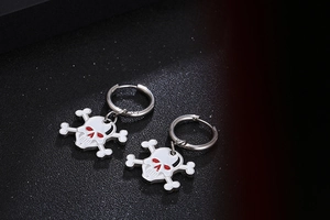 Macro detail of skull and crossbones earrings with white enamel and red eye accents