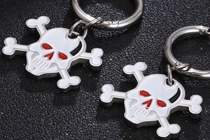 Macro shot of skull and crossbones earrings with white enamel and red eye details