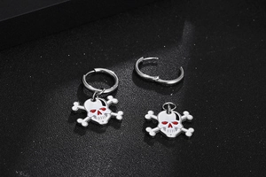 Detail of skull and crossbones earrings with white enamel and red eye accents on black