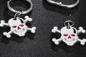 Macro shot of punk skull earrings with white enamel and red eye detail on black texture