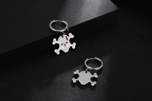 Detailed view of silver skull crossbones earrings on a dark textured background