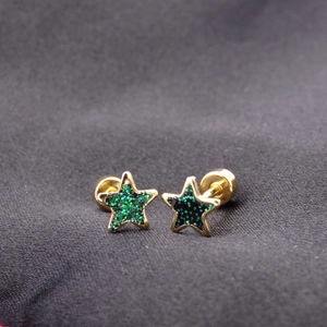 Macro detail of star-shaped titanium earrings with green glitter inlay and screw back