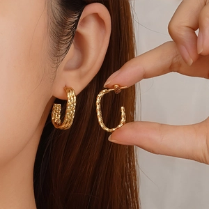 Polished gold twisted rope C-shaped earrings in hollow geometric design on model