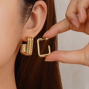 Gold geometric rectangle earrings with textured weave details shown on an ear model