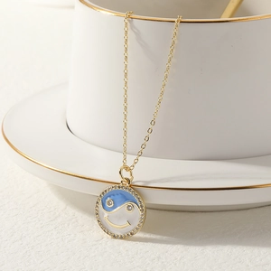 Detail of yin-yang smiley face pendant with blue enamel and crystal bezel on gold chain