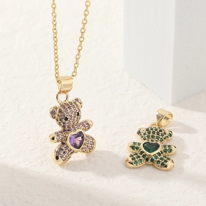 Close-up of gold bear necklace featuring purple and green cubic zirconia heart stone