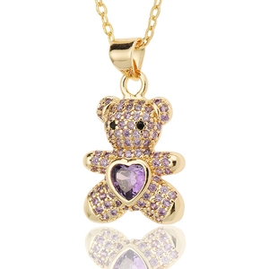 Macro detail of golden bear pendant featuring purple heart stone and pavé setting
