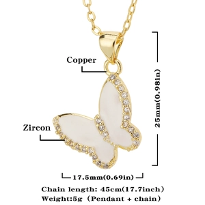 Detailopname van gouden vlinderketting met wit emaille vleugels en zirkoon
