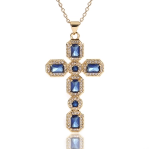 Detail van gouden kruishanger met blauwe zirkoon en witte diamanten steentjes