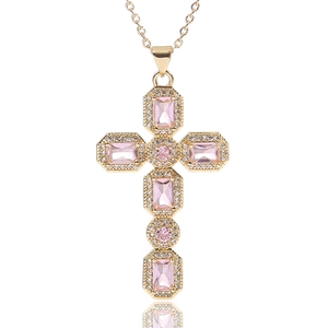Macro-detail van gouden kruishanger met grote roze zirkonia's en kleine heldere diamanten
